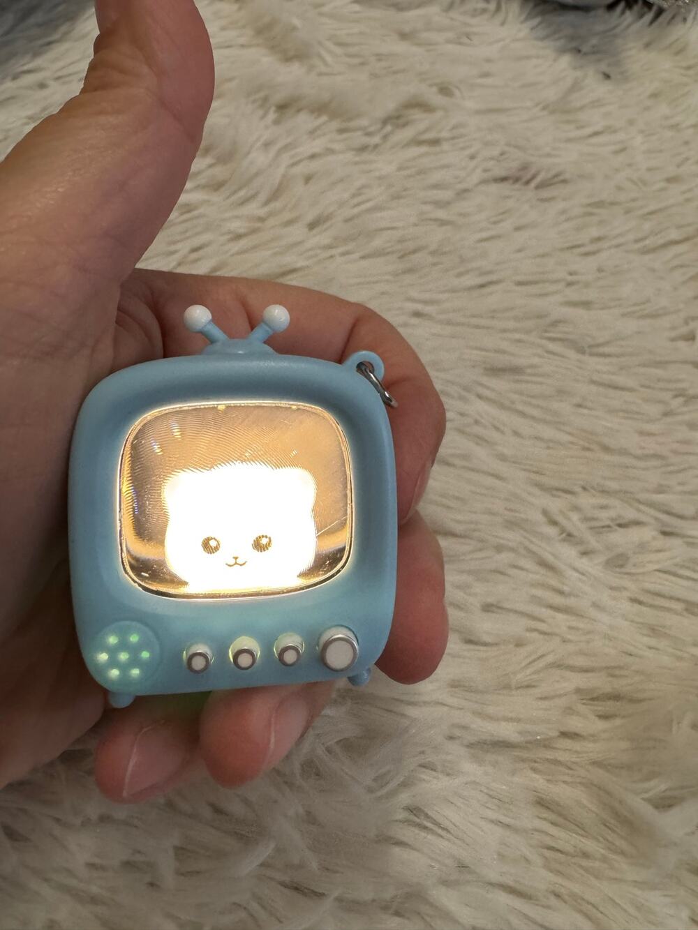 Small white cat in a blue Tv clicker keychain light up  super cute!!